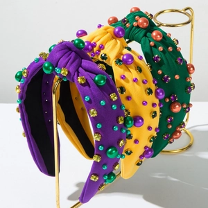 Three knot headbands with colorful pearls and rhinestones on a gold display rack