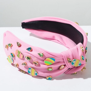 Détail d'un serre-tête rose noué avec strass colorés et ornements d'oeufs de Pâques