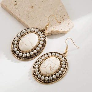 Macro detail of vintage gold earring with oval marble stone and pearl border