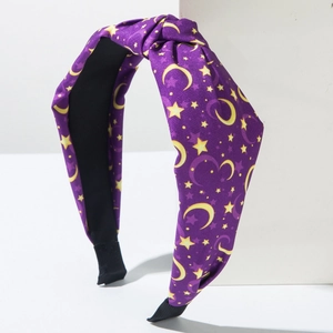 Close-up of knotted purple fabric headband featuring yellow star and moon celestial patterns