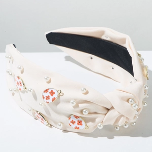 Detailaufnahme des beigen Knotenstirnbands mit weißen Perlen und floralen Anhängern