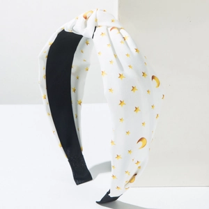 Close-up of white knotted headband with yellow star and moon print on twill fabric