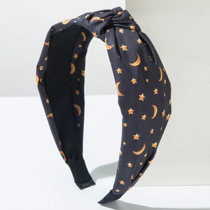 Detail of knotted black fabric headband with yellow star and moon print on plaster block