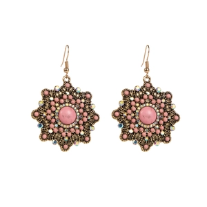 Detailed close-up of ethnic star-shaped drop earrings with pink stones and crystals