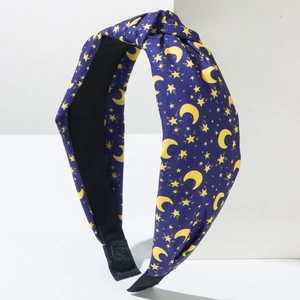 Detail of dark blue fabric knotted headband with yellow moon and star patterns