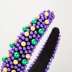 Gros plan de perles colorées sur un serre-tête large avec perles mauves, vertes et dorées