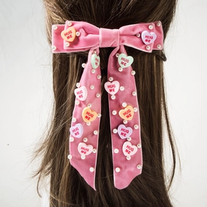 Roze fluwelen haarstrik met parels en hartjes op lang golvend haar bevestigd