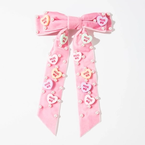 Detail van roze fluwelen strik haarspeld met parels en kleurrijke Hug Me hartjes