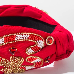 Gros plan d'un serre-tête rouge avec motifs de perles en cœur et strass brillants
