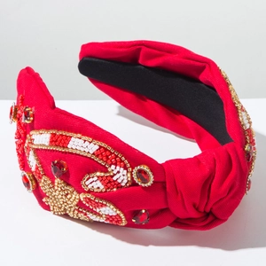 Détail d'un serre-tête rouge à nœud avec perles artisanales et motifs de cœurs brillants