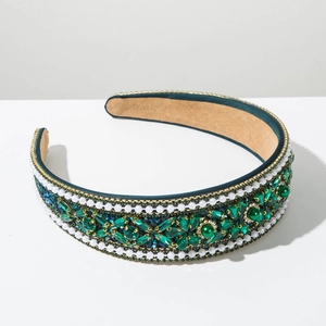 Close-up of luxury Baroque headband with green crystals and white pearls on satin
