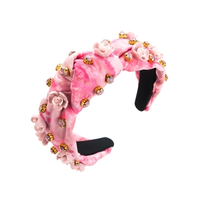 Gros plan détaillé sur un serre-tête fleuri rose avec cristaux et tissu effet tie-dye