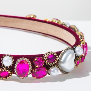 Gros plan du serre-tête en velours avec gemmes roses, perles blanches et accents baroques