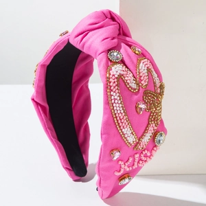Détail du serre-tête rose à nœud avec motif cœur perlé et strass multicolores