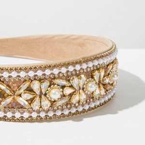 Detail of baroque pearl headband with intricate rhinestones on champagne satin fabric