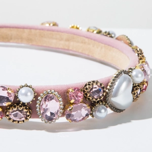 Vue macro d'un serre-tête en velours rose avec cristaux, perles et cœur perlé