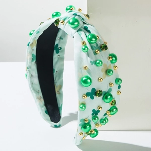 Détail d'un serre-tête noué bleu clair avec perles vert émeraude et trèfles à quatre feuilles