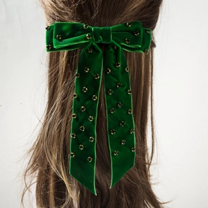 Détail d'une pince à cheveux nœud en velours avec perles noires et dorées sur cheveux