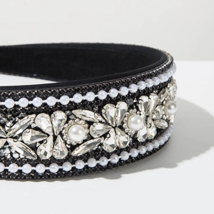 Macro detail of luxury baroque headband featuring intricate pearls and crystals on black fabric