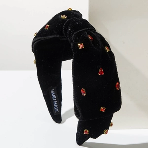 Dettaglio del cerchietto in velluto nero con strass rossi ed etichetta fatta a mano