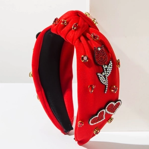 Dettaglio di un cerchietto annodato rosso con strass e applicazioni a cuore e tulipano