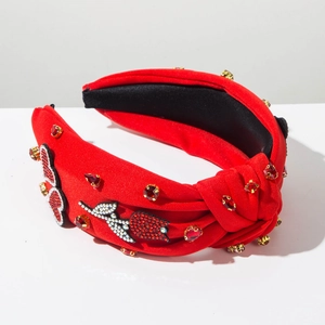Dettaglio del cerchietto rosso annodato con rose di strass e decorazioni di cristallo