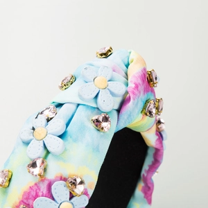 Détail d'un serre-tête en tissu tie-dye avec fleurs 3D bleues et strass roses brillants