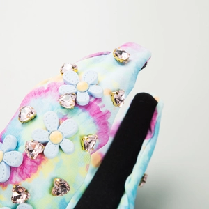 Macro d'un serre-tête en tissu tie-dye avec fleurs 3D et strass en forme de cœur rose