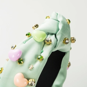 Gros plan d'un serre-tête en satin vert menthe avec cœurs colorés et strass brillants