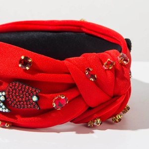 Dettaglio di cerchietto rosso con nodo, cristalli scintillanti e decorazione a tulipano