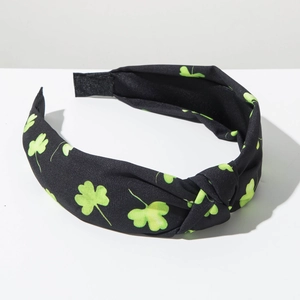 Detail of St. Patrick's Day wide knotted headband with green clover print on black fabric