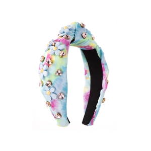 Détail du bandeau tie-dye avec fleur en résine bleue et décorations en strass cœur rose