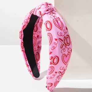 Close-up of pink knotted headband featuring red hearts and XO patterns on knit fabric
