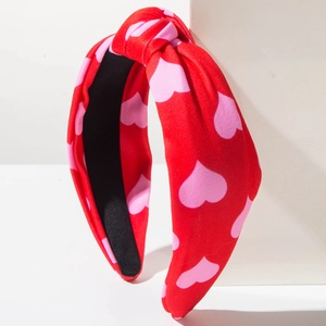 Close-up of red knotted headband with pink heart print and non-slip black lining