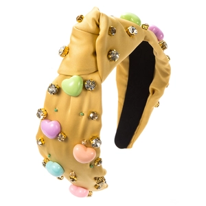 Détail d'un serre-tête jaune noué avec des perles de cœur colorées et strass brillants