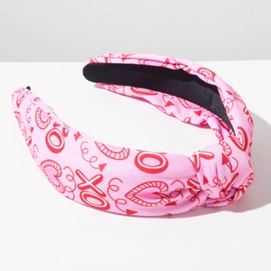 Detail of pink fabric headband with red heart and XO print showing fabric knot and texture