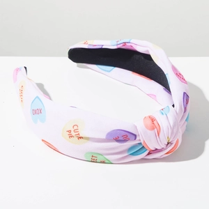 Detail of pink knotted headband with heart patterns and sweet text for Valentine's Day