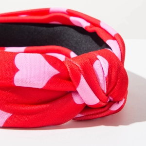 Close-up detail of red fabric headband with pink hearts and a stylish knot design