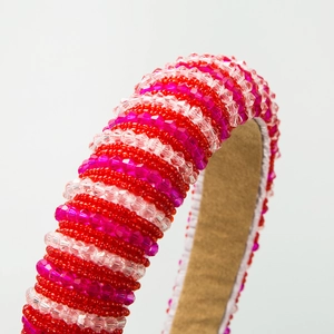 Détail d'un serre-tête perlé rose et rouge avec cristaux et doublure douce en velours