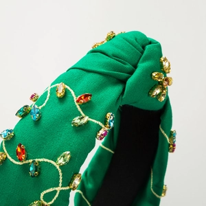 Macro detail of green knotted headband featuring colorful rhinestones and gold embroidery