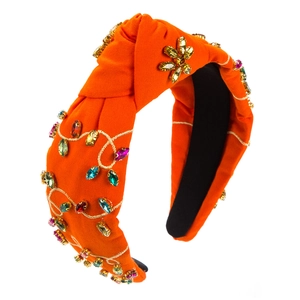 Close-up of orange knotted headband with colorful rhinestones and gold vine embroidery