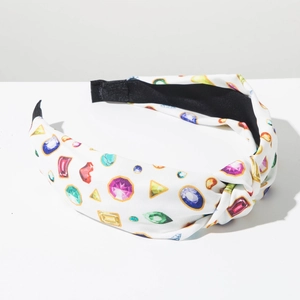 Detalle de diadema blanca con nudo e estampado de gemas de colores y forro negro antideslizante