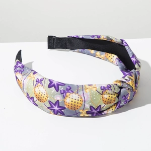 Detalle de la tela estampada con estrellas de colores en una diadema con nudo festiva