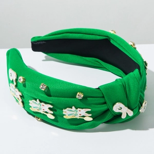 Détail d'un serre-tête en tissu vert orné de charmes lapin et de strass étincelants