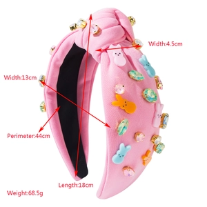 Détail d'un serre-tête rose noué orné de breloques lapin colorées et de strass brillants