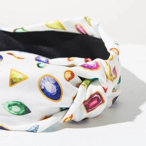 Detalle de diadema blanca con nudo, estampados de gemas de colores y forro antideslizante