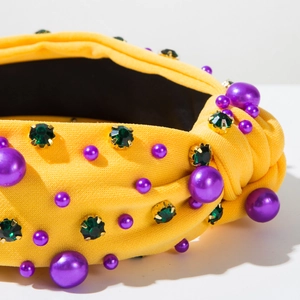 Gros plan d'un serre-tête noué jaune orné de perles violettes et pierres vertes