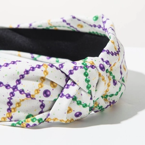 Detalle de diadema anudada de Carnaval con patrones de cuentas de colores sobre tela blanca