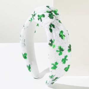 Detail of St. Patrick's Day knotted headband with green shamrock sequins on white fabric