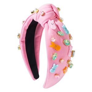 Détail d'un serre-tête en maille rose avec des strass colorés et breloques de lapin